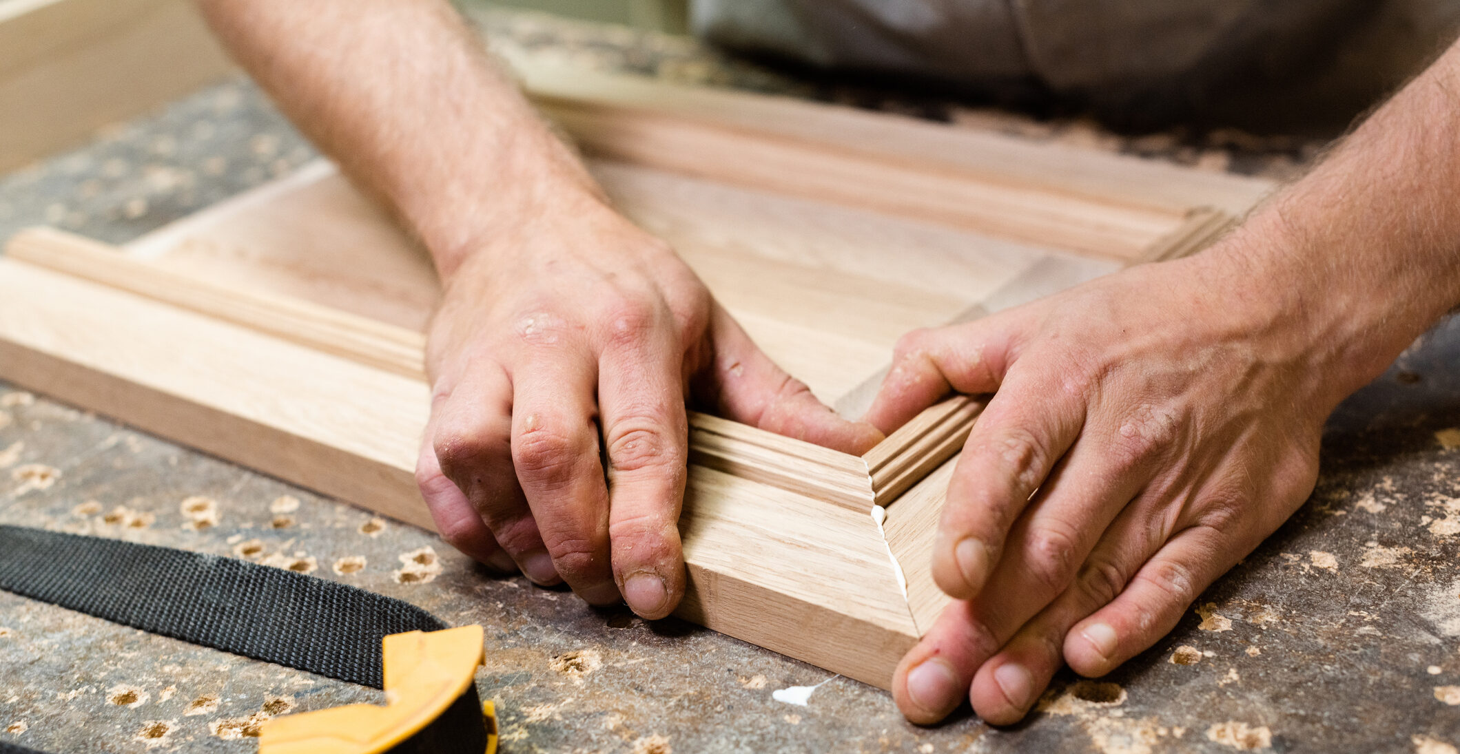 Wood worker holding together two wood pieces with glue on the sides