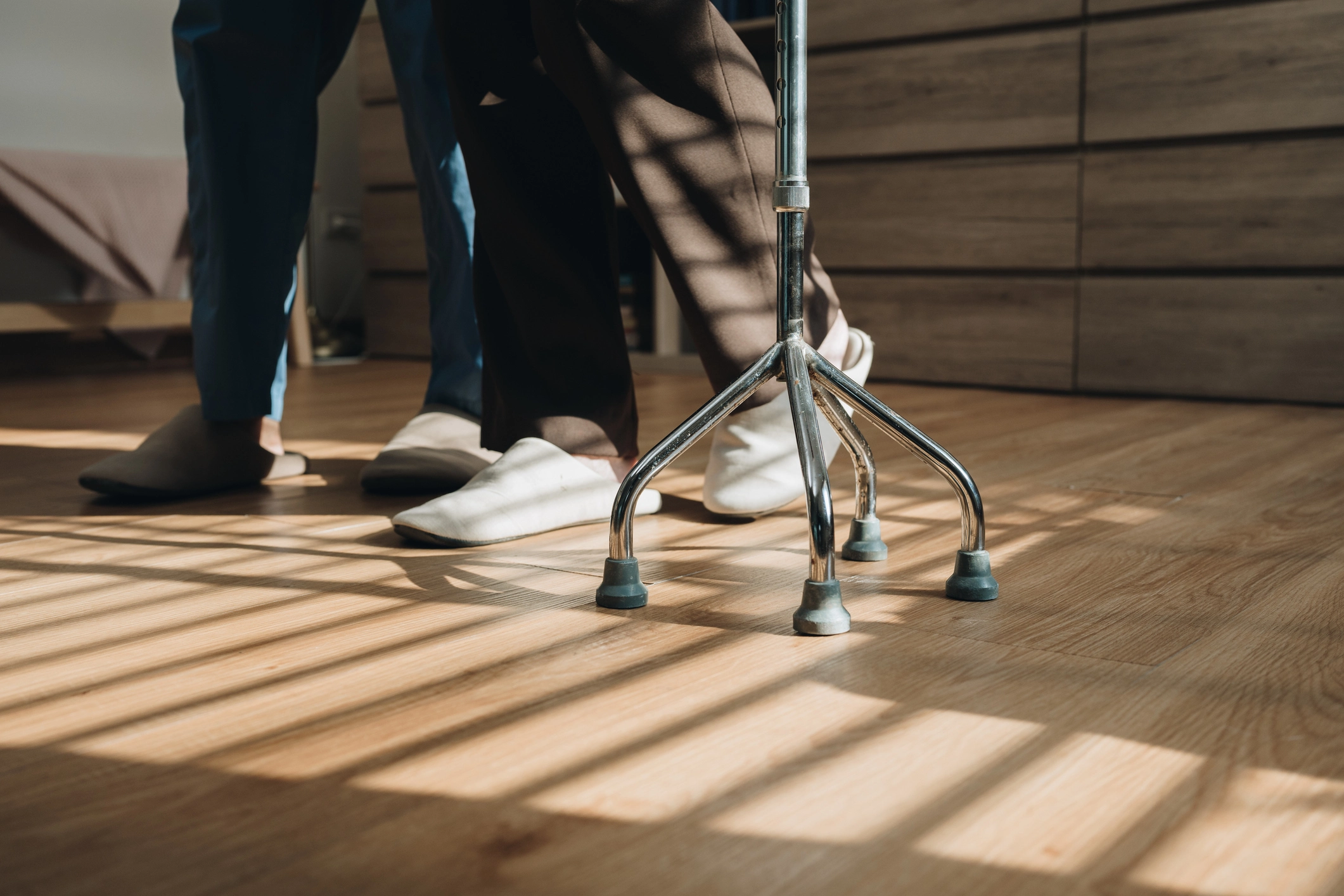 Close-up of assisted living resident and caregiver walking on clean, low-emission flooring with a walker, emphasizing safety and accessibility.