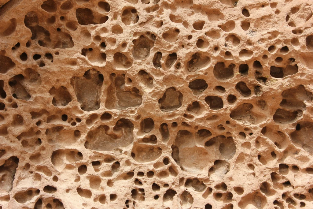 Close-up of a porous, pitted surface illustrating how microscopic voids in floor coatings can trap moisture, debris, and contaminants.