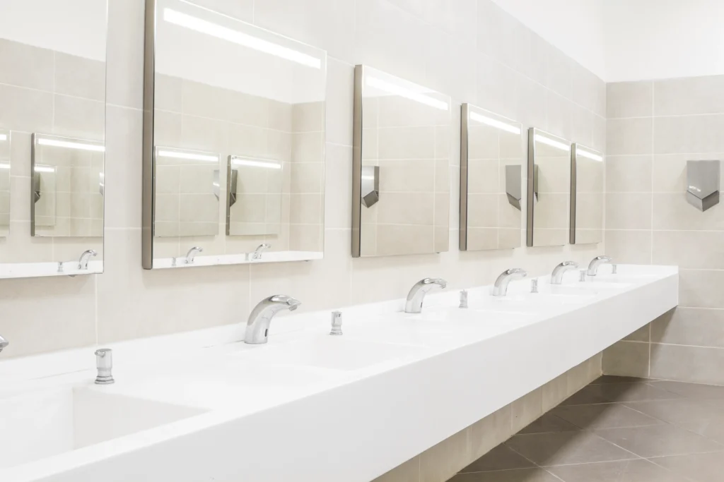 Public restroom sink area with mirrors and seamless countertops designed to support hygiene and resist surface degradation from frequent use.