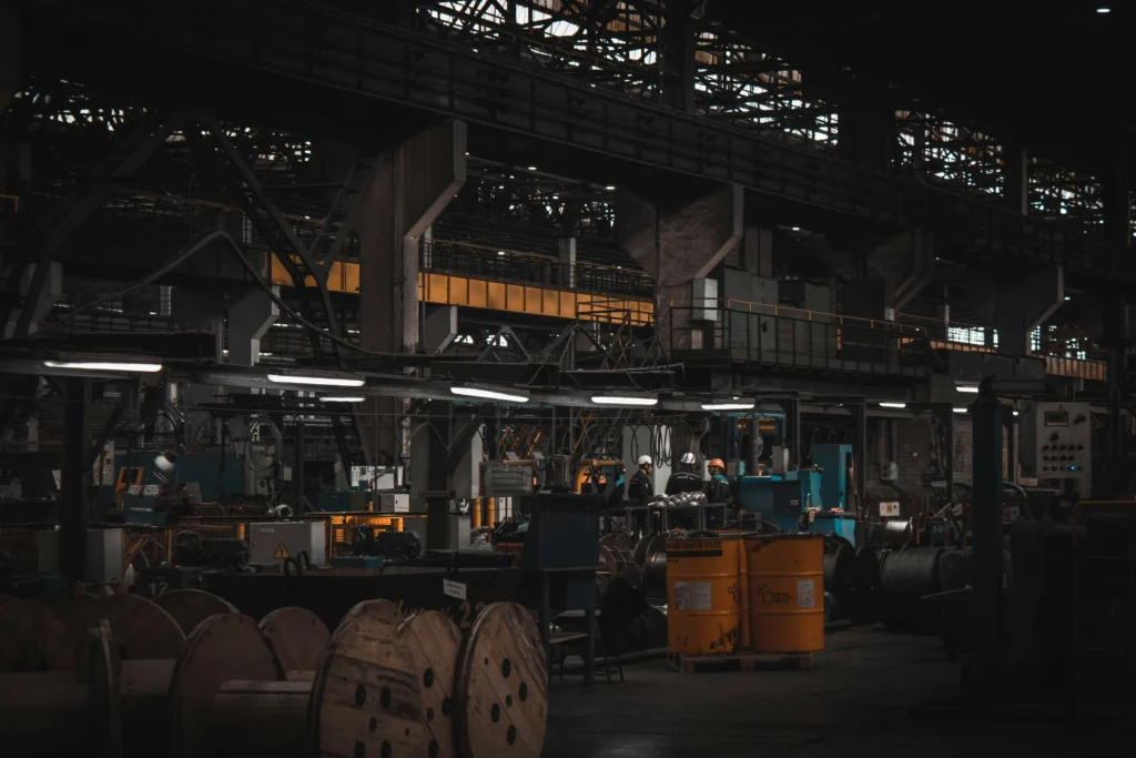 Interior of a heavy manufacturing facility showing machinery and equipment where long-term coating breakdown can release particulates and contaminants.