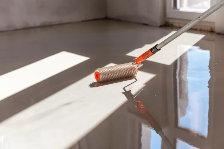 Applying low VOC epoxy and urethane floor coating with a textured roller in a commercial space.