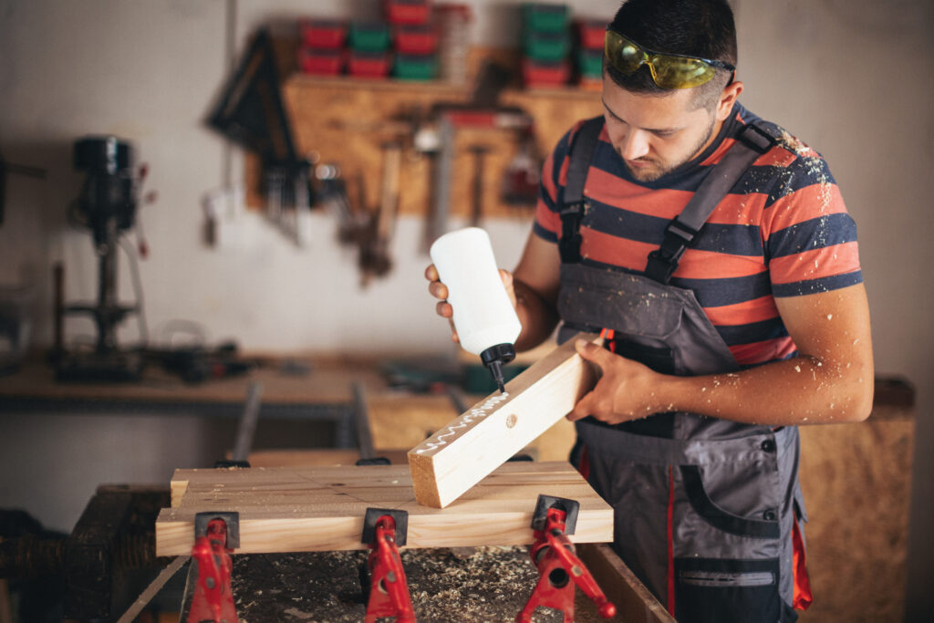 Young carpenter glueing wood