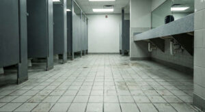 Public restroom floor with tiled surface exposed to moisture, heavy foot traffic, and contamination risk, highlighting the need for public restroom floor coatings
